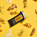 SVRY supplement bar surrounded by turmeric roots and seeds on a yellow background