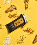 SVRY supplement bar surrounded by turmeric roots and seeds on a yellow background