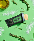 SVRY rosemary olive oil protein bar with rosemary sprigs, olive oil and sea salt on a green background