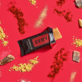 SVRY barbecue protein bar surrounded by spices, garlic cloves and smoked wood chips on a red background