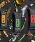 savory protein bars on a dark background with spices and ingredients around them