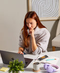 Woman working on a laptop at a desk in a home office setting with a SVRY bar on her notebook