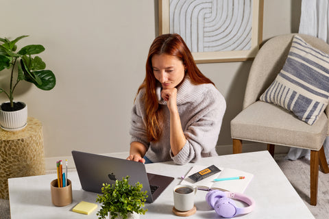 Woman working on a laptop at a desk in a home office setting with a SVRY bar on her notebook