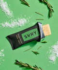 SVRY protein bar on a green background with rosemary leaves and salt crystals.