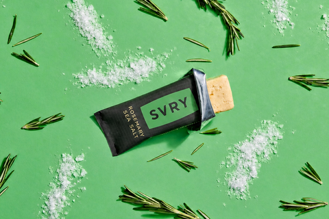 SVRY protein bar on a green background with rosemary leaves and salt crystals.