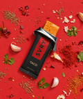 SYVR Taco protein bar surrounded by spices and herbs on a red background